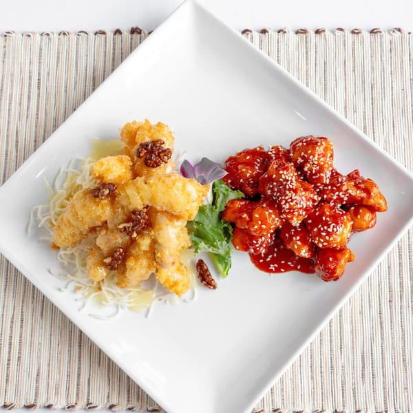 A white square plate with two piles of chicken: honey walnut and General Tso's.