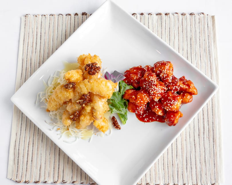 A white square plate with two piles of chicken: honey walnut and General Tso's.