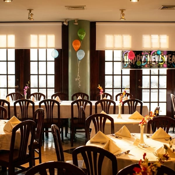 Restaurant dining room set for a New Year's celebration with tables, chairs, and balloons.