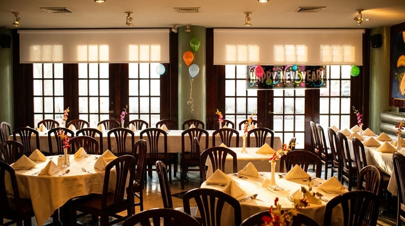 Restaurant dining room set for a New Year's celebration with tables, chairs, and balloons.